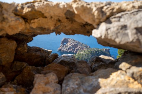 Blick durch einen Felsen auf einen großen Felsen im Meer 