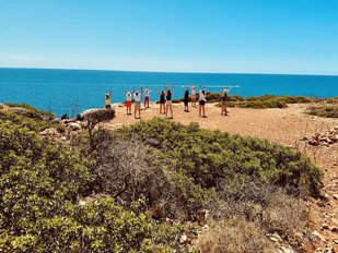 Eine Gruppe praktiziert Yoga auf einem Felsen am Meer