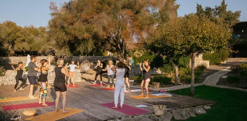 Yoga Übende auf einer Yogaplattform unter blauem Himmel